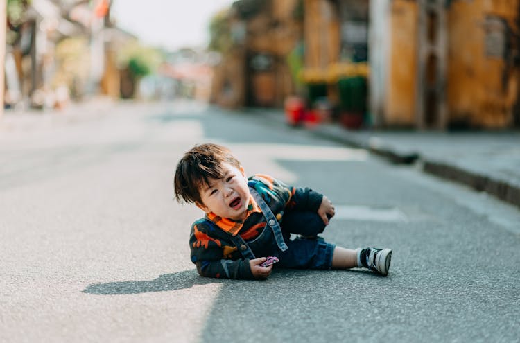 Crying Asian Boy Lying On Road