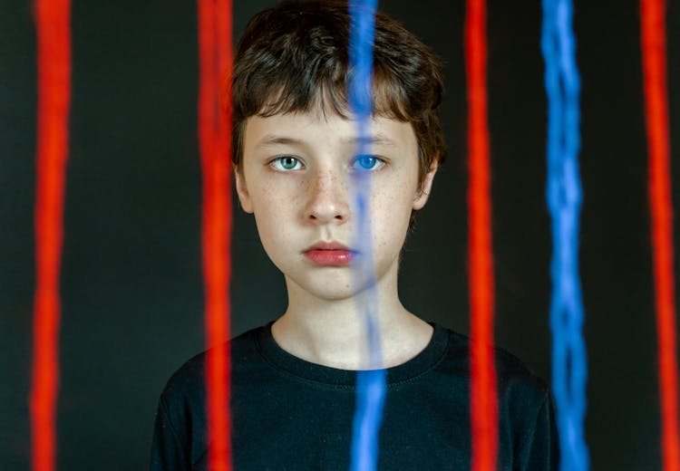 Boy In Black Crew Neck T-shirt Behind Red And Blue Strings