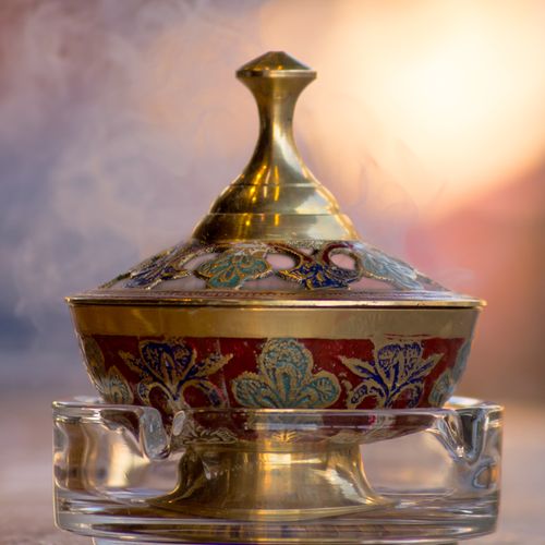 Free Ornate brass incense burner with intricate floral designs emitting gentle smoke, ideal for traditional decor. Stock Photo