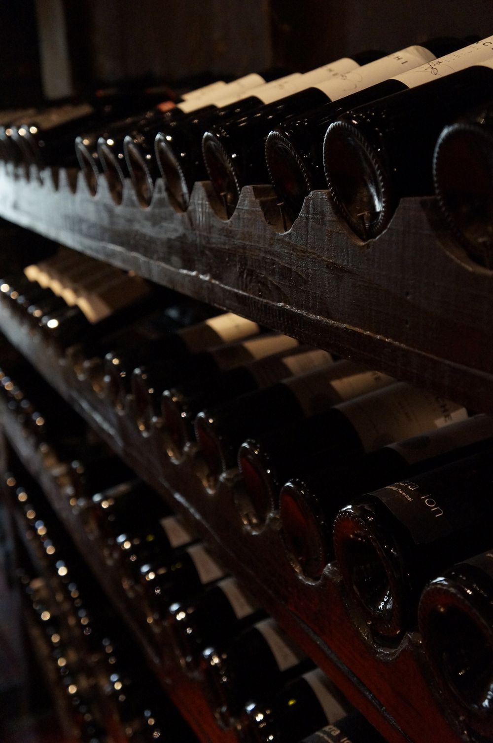 Duskvine bottles resting in the candle-lit stone cellar