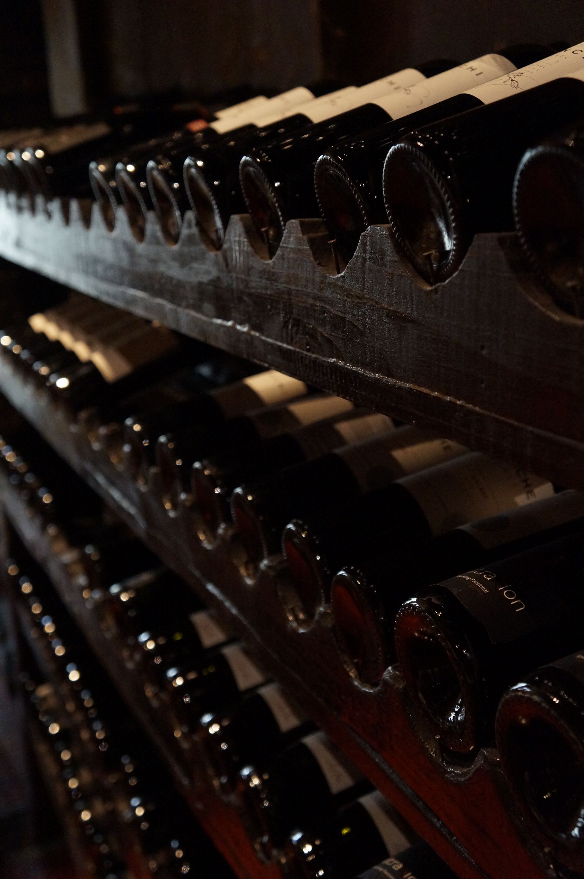 Rows of red wine bottles ageing in wooden cellar racks