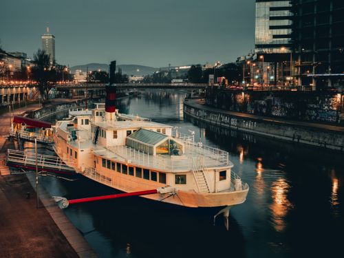 Free A serene night scene of a docked boat on the Donaukanal in Vienna, Austria, showcasing urban reflections. Stock Photo