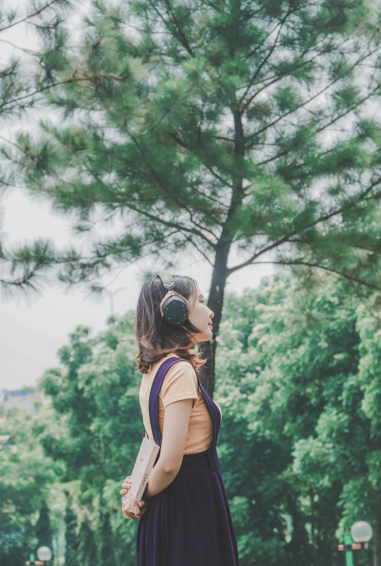 Young Woman In The Park Listening To Music Using Headphones