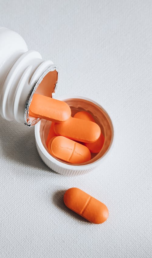 Orange Medication Pill on White Plastic Bottle