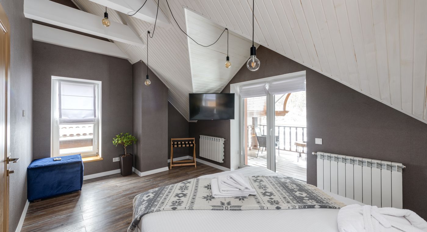 A modern hotel room with a large bed and balcony in the morning light
