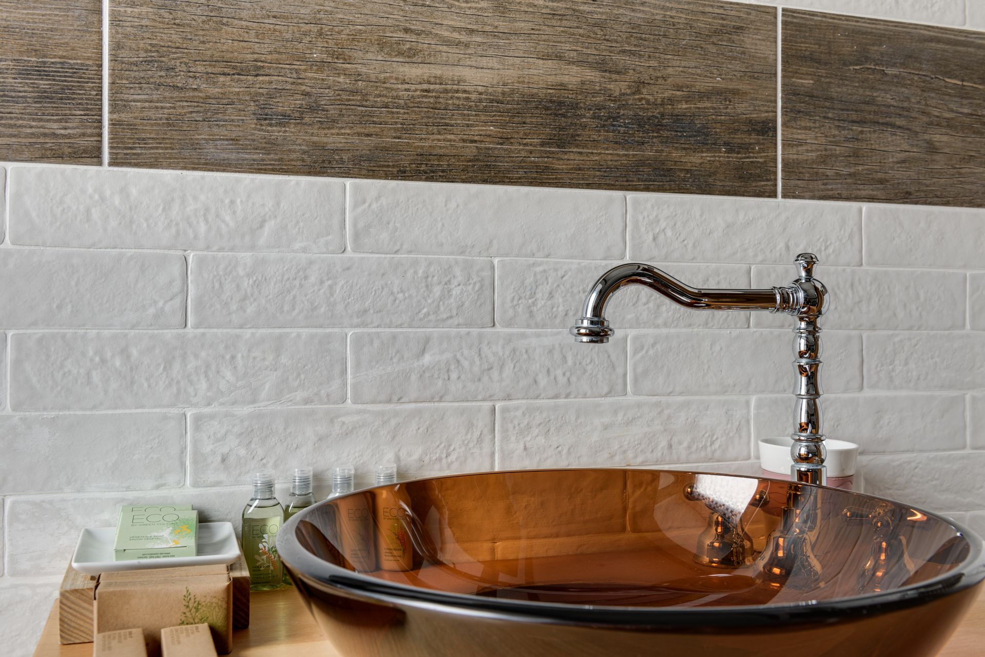 Elegant bathroom interior featuring a glass bowl sink with sleek chrome faucet and stylish tile backdrop.