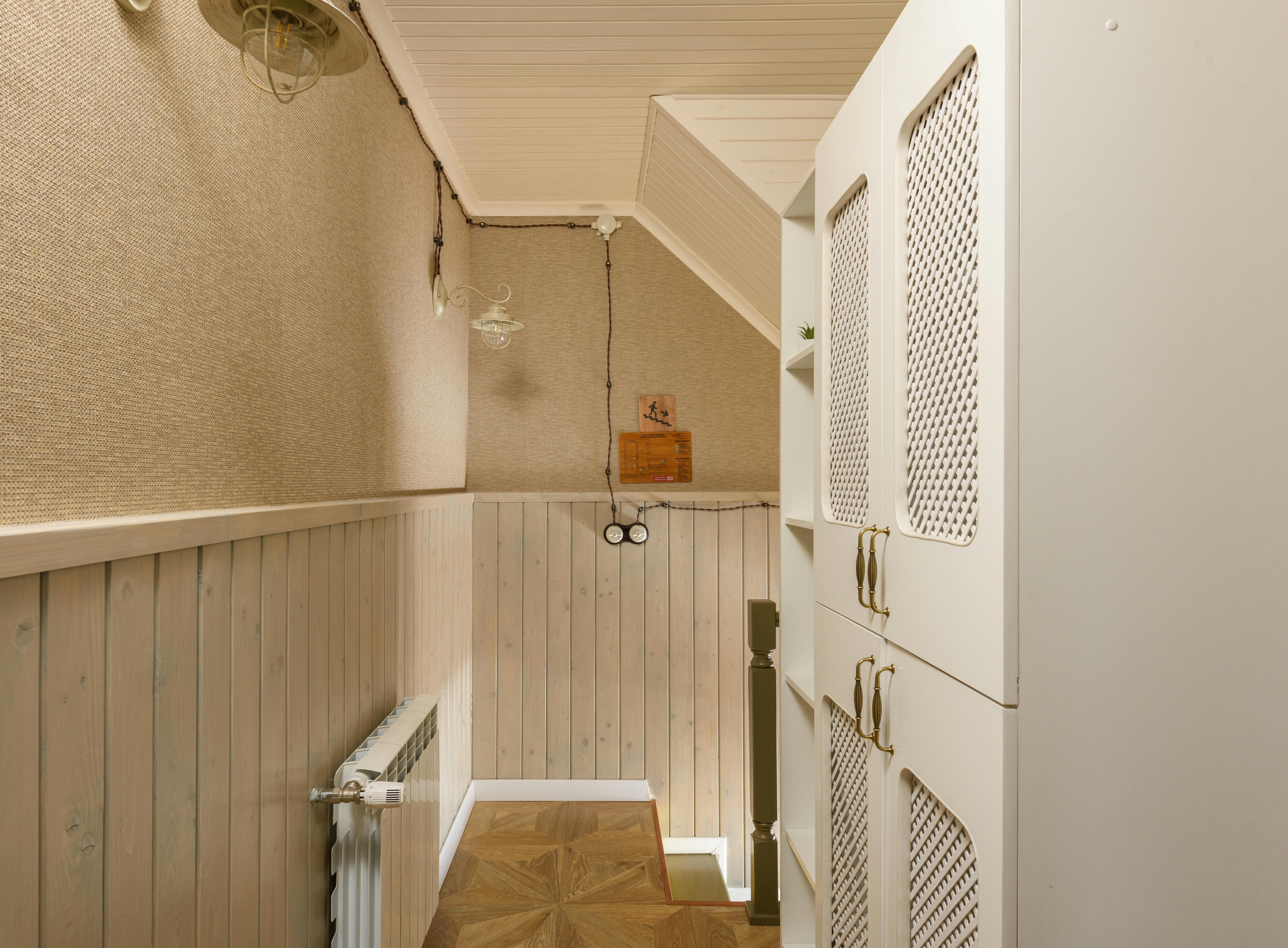 Wnętrze wąskiej szafy w korytarzu z półkami, drążkiem i listwą LED