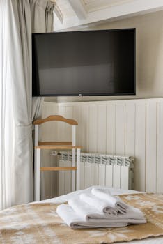 Cozy hotel room featuring a television and freshly folded towels on the bed.