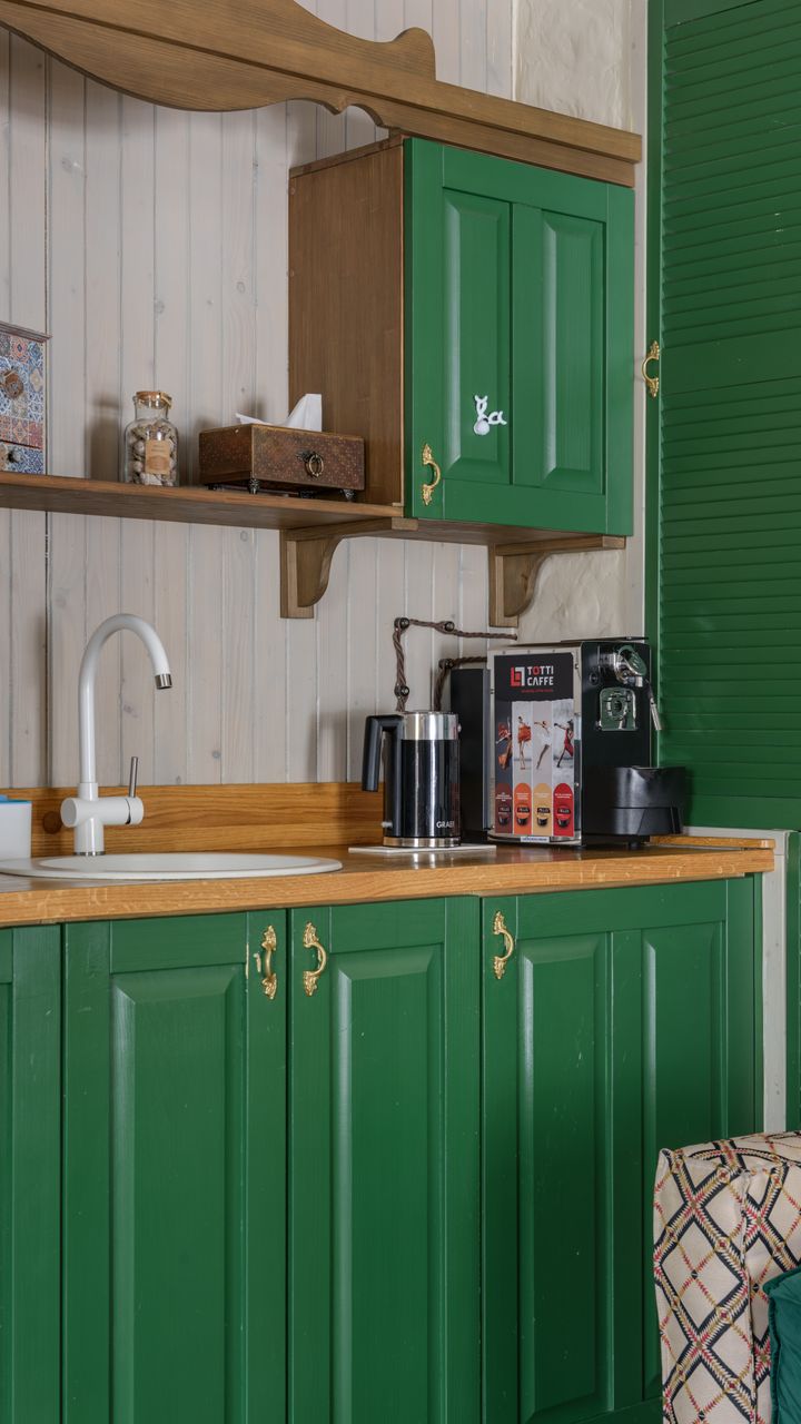 A bright kitchen open shelf coffee bar cabinet displaying mugs, coffee beans, and barista tools