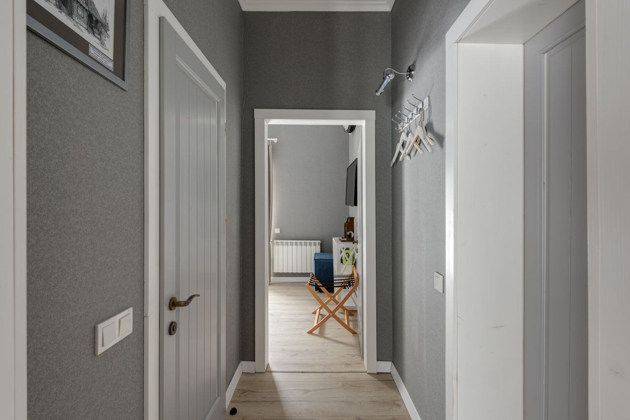 Grey hallway with white-trimmed interior doors and coat hooks