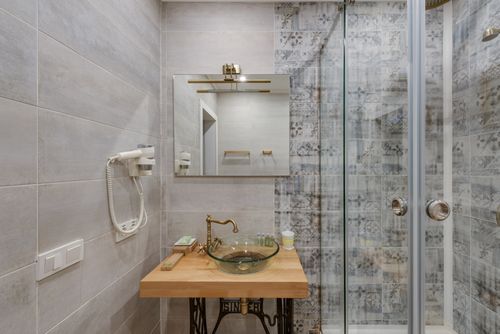 Free Elegant modern bathroom featuring glass shower, vintage sink, and decorative tiles creating a stylish ambiance. Stock Photo