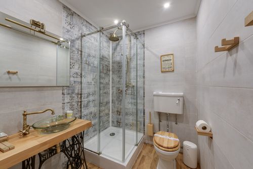 Free Stylish bathroom featuring a glass shower, wooden sink and toilet seat, and modern decor. Stock Photo