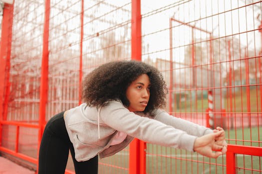A woman stretching on an outdoor sports court, focusing on fitness and wellness.