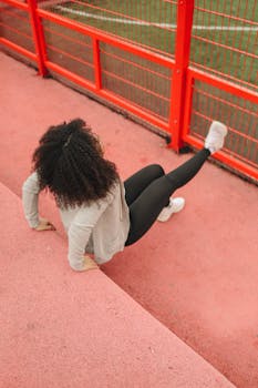 Fitness woman stretching on a red bridge outdoors, emphasizing wellness.