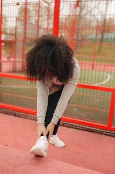 A woman in sportswear stretches in a vibrant outdoor park setting.