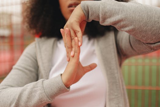 Close-up of a woman stretching hands outdoors wearing a gray jacket, perfect for lifestyle and fitness themes.
