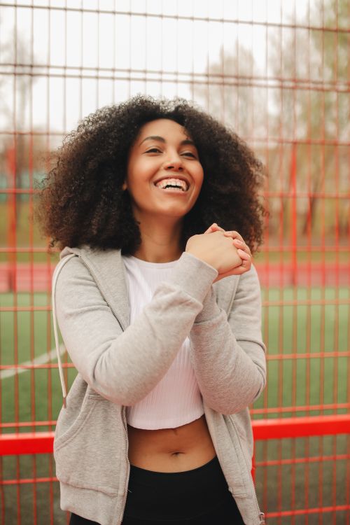 Free Smiling woman with curly hair enjoying outdoor exercise in sportswear. Stock Photo