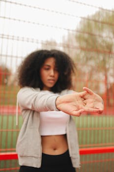 African American woman in a crop top stretching outdoors, focusing on wellness and fitness.