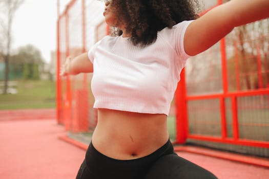 A woman with curly hair stretching outdoors, promoting health and wellness.