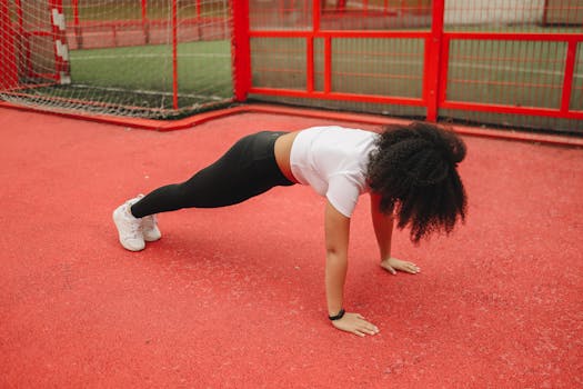 A woman doing planks on a colorful outdoor sports field, embracing a healthy lifestyle.
