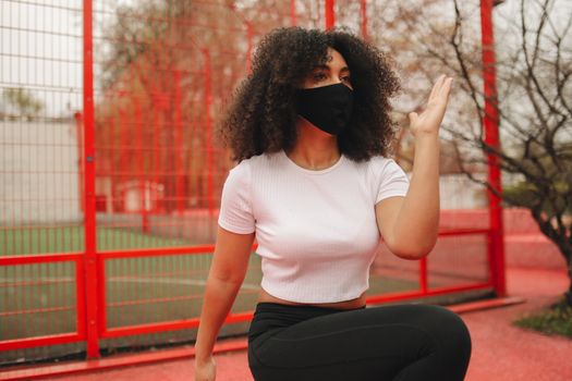 Woman in White Crew Neck T-shirt and Black Pants Sitting on Red Metal Fence during