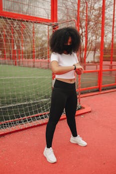 Woman checking fitness tracker during outdoor workout in sports gear.