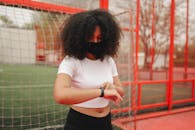 Woman in White T-shirt and Black Skirt Standing Near Red Metal Fence