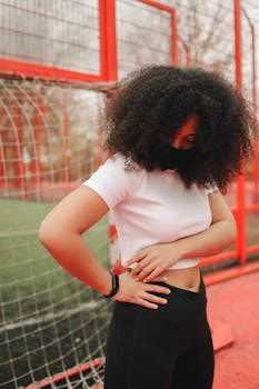 A young woman with curly hair and a fitness tracker in a sporty outdoor setting.