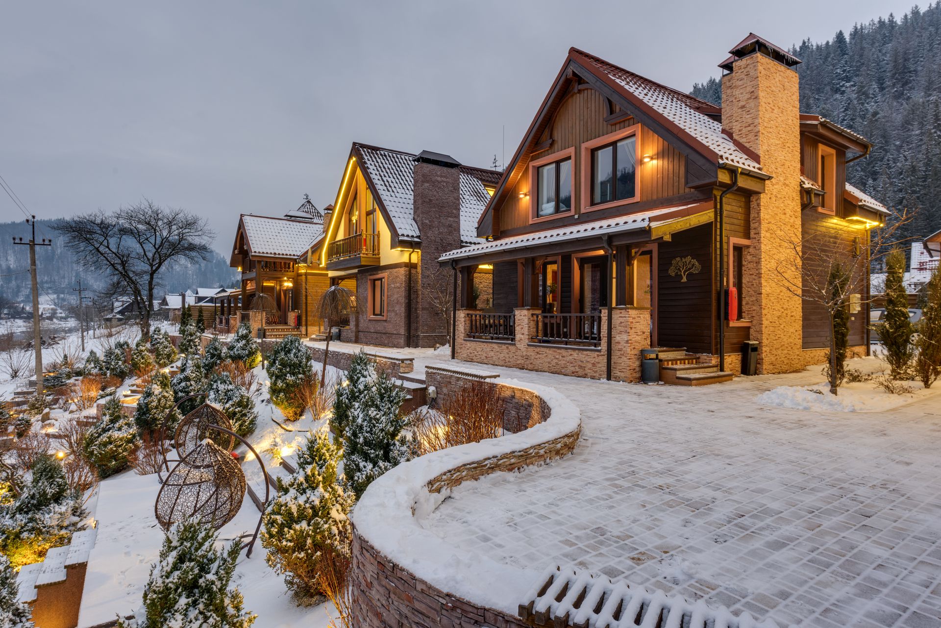 Cozy illuminated chalets nestled in snowy mountain scenery, perfect winter getaway.