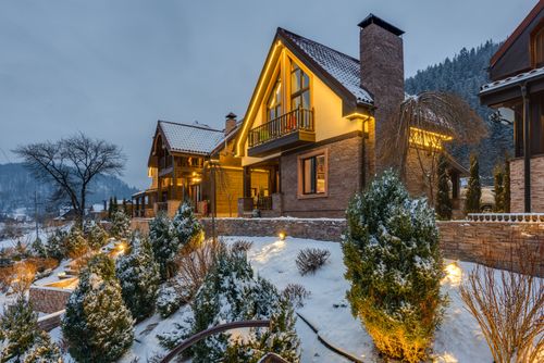 Free Warmly lit chalet surrounded by snow-covered trees in a picturesque winter setting. Stock Photo