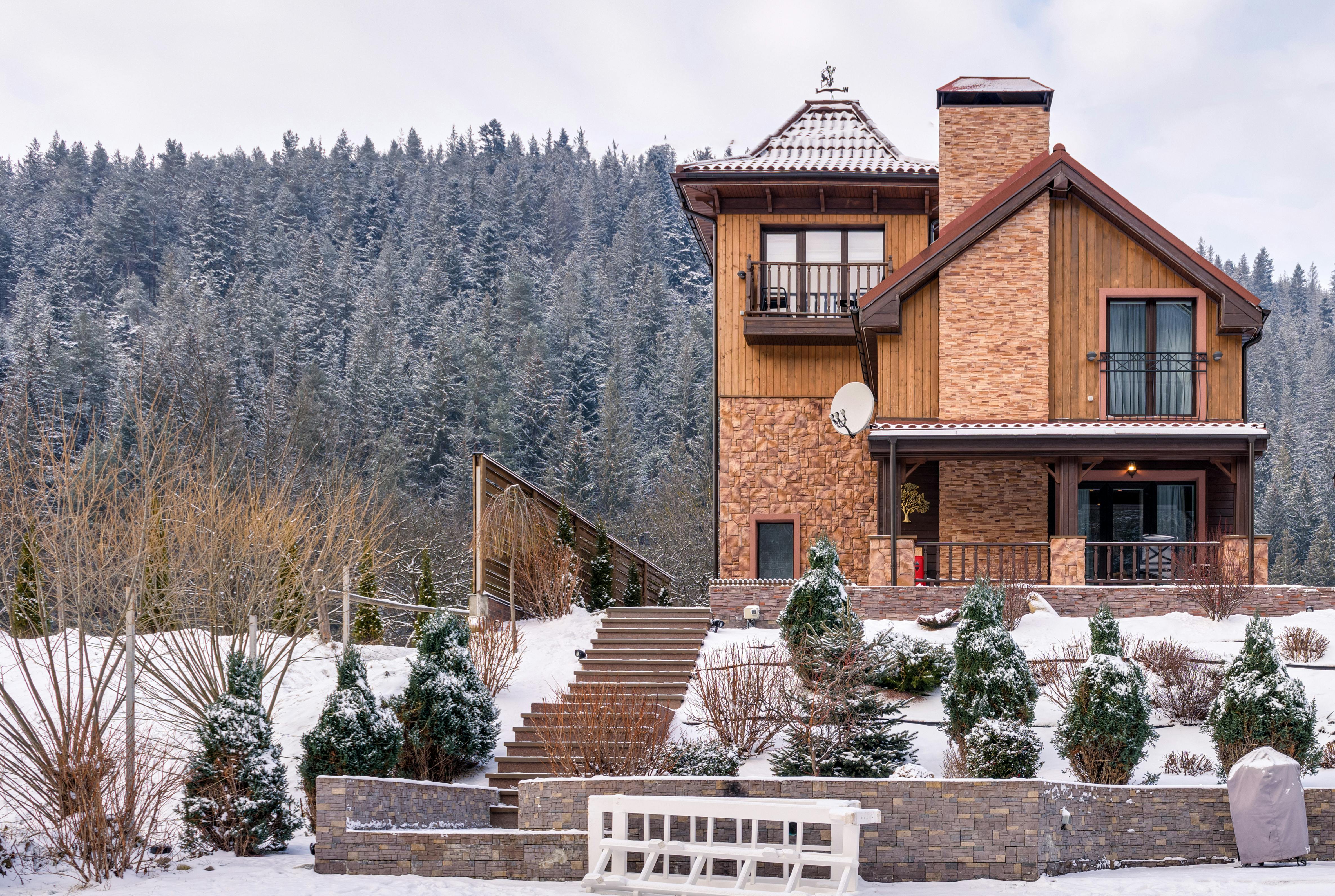 A picturesque chalet in winter with snow-capped terrain and a serene forest backdrop.