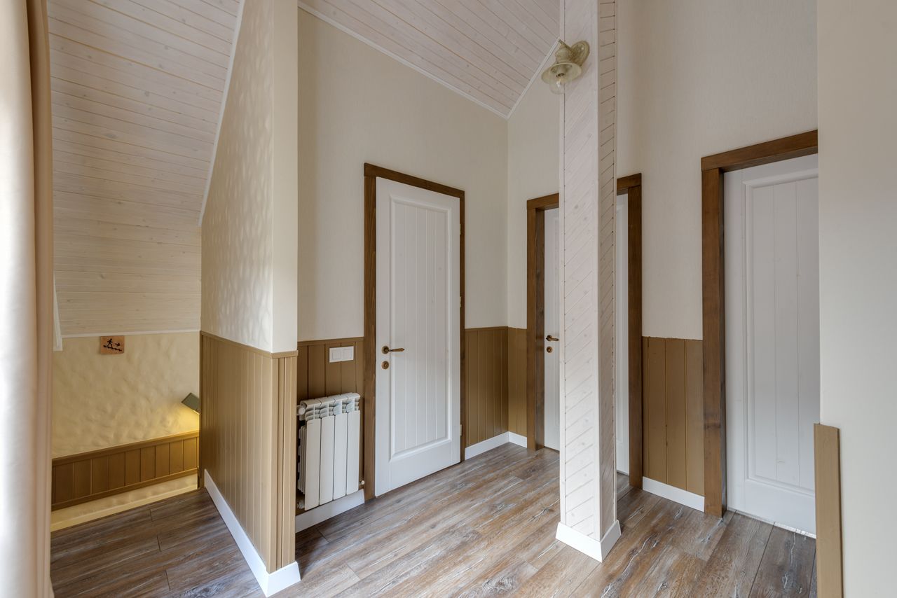 Hallway in a modern chalet with white panelled doors and wood panelling