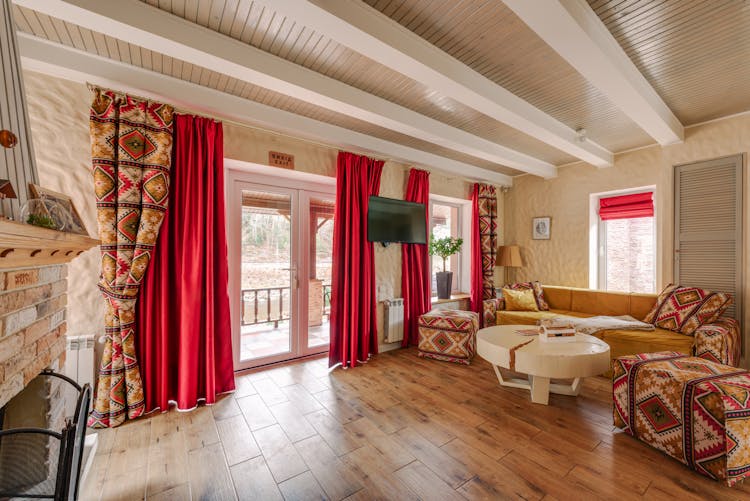 Contemporary Living Room Interior With Patterned Curtains, Cushions And Poufs