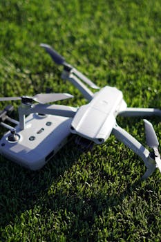 A detailed shot of a drone with controller on a lush green grass field.