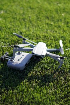 A close-up of a small drone and controller placed on vibrant green grass in daylight.