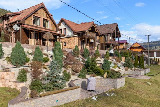Rustic houses with sloped roofs and landscaped gardens under clear blue skies. Ideal for real estate visuals.