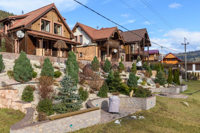 Timber houses with pitched roofs above a terraced rock garden, photo by Max Vakhtbovych on Pexels