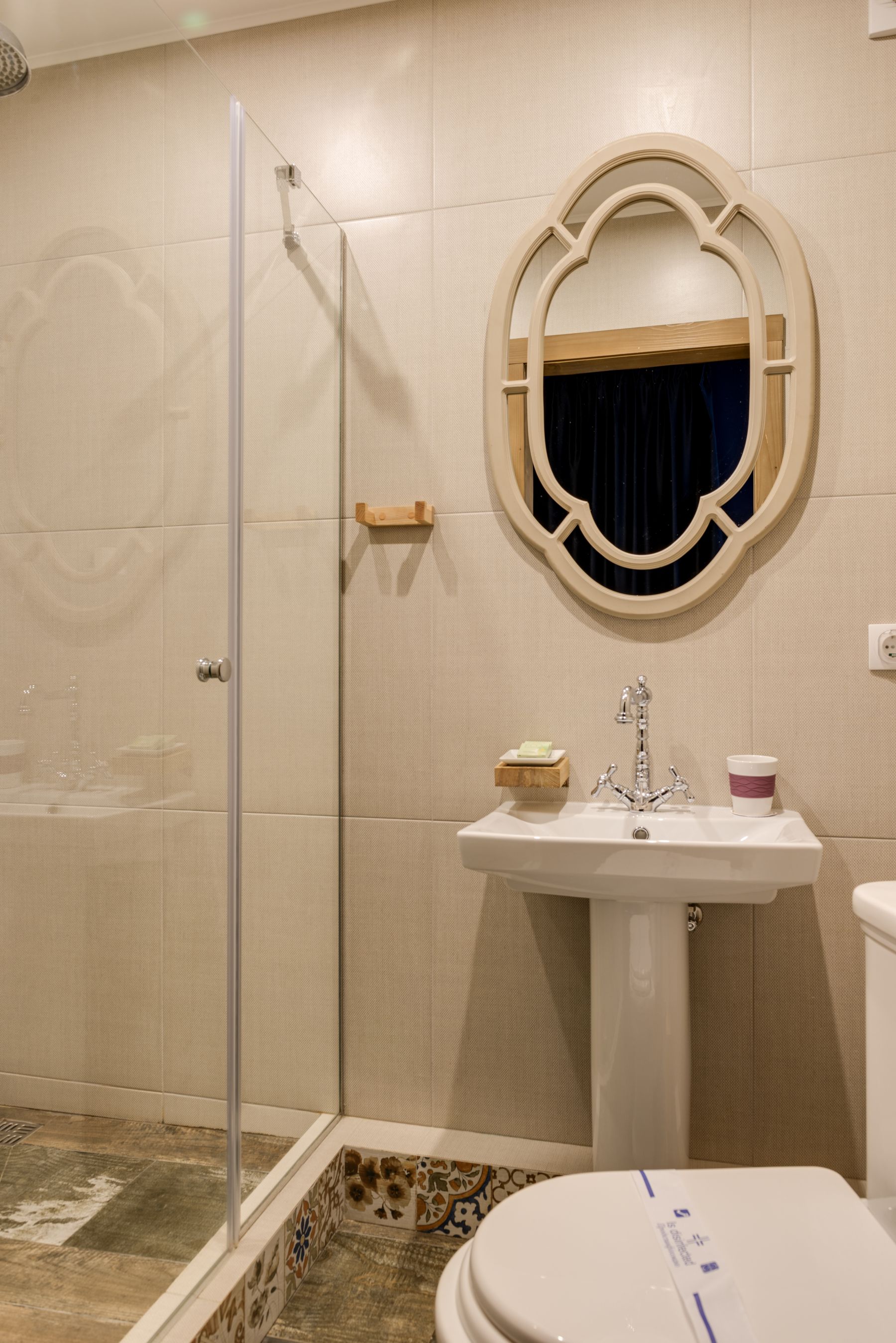 Bathroom with pedestal sink, ornate framed mirror and restrained surrounding finishes