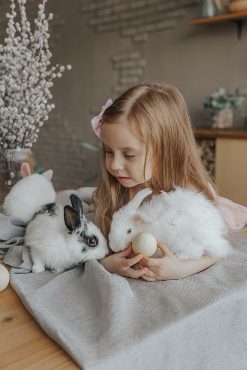Free Adorable little child lying on table with eggs and fluffy bunnies during Easter holiday at home Stock Photo