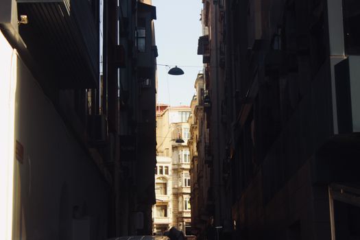 Stunning architectural view of a narrow street with sunlight peeking through tall buildings.