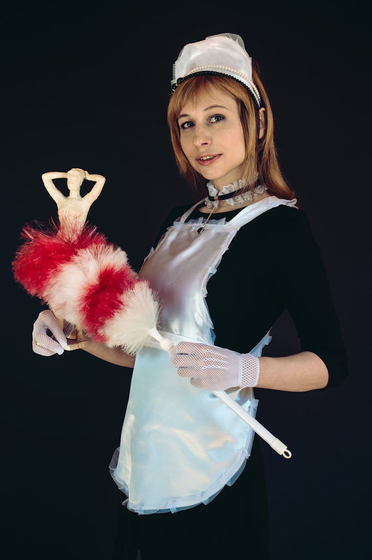 Smiling Woman In Black Dress And White Apron Dusting Statuette