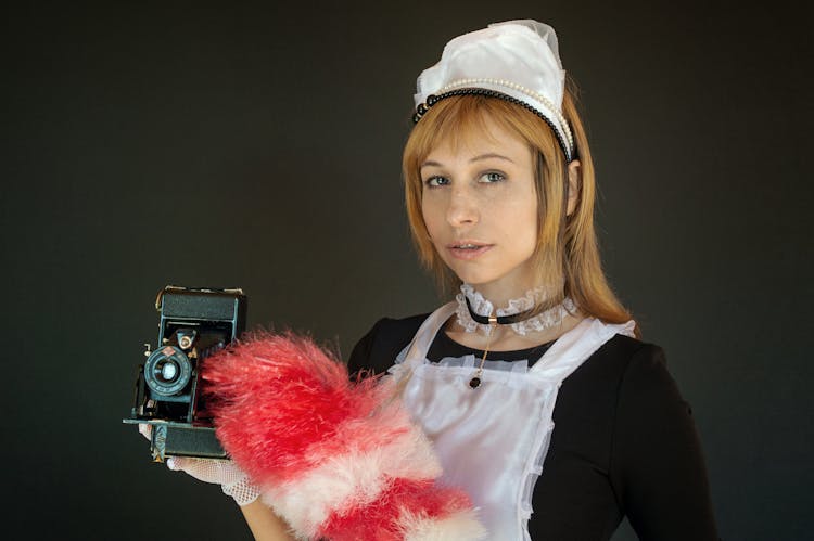 A Woman In A Maid Outfit Holding A Camera