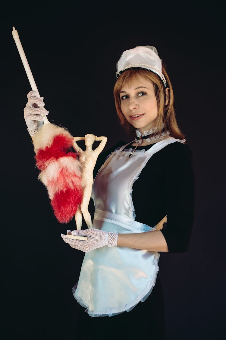 A Woman In A Maid Outfit Holding A Figurine