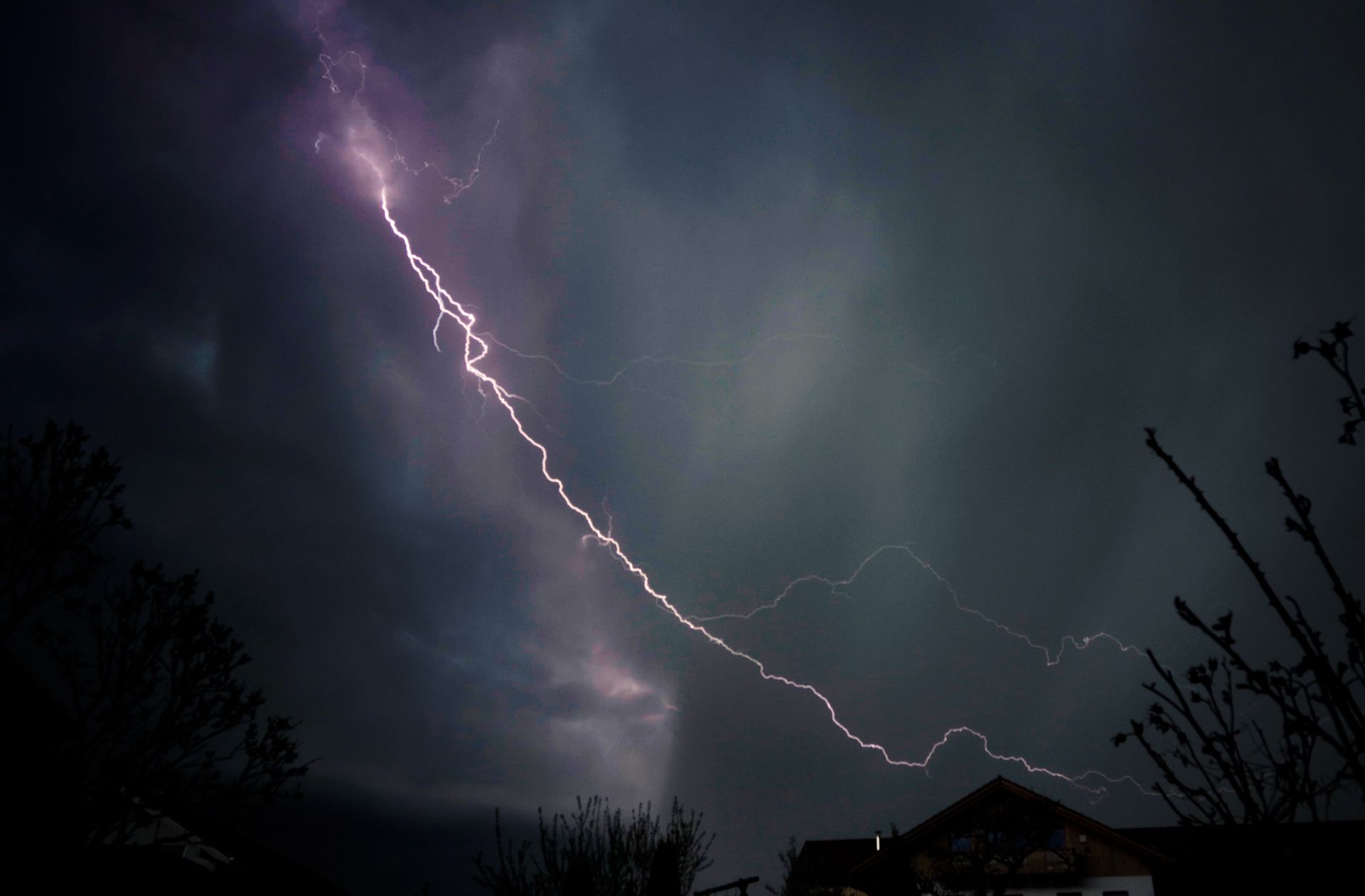 A vivid lightning strike illuminates a dark night sky, creating a dramatic weather scene.