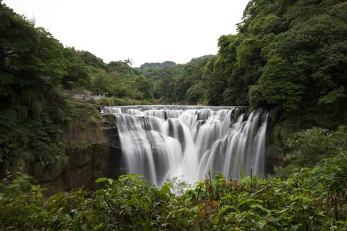 Free A tranquil waterfall cascades amid dense forest greenery, capturing serene natural beauty. Stock Photo
