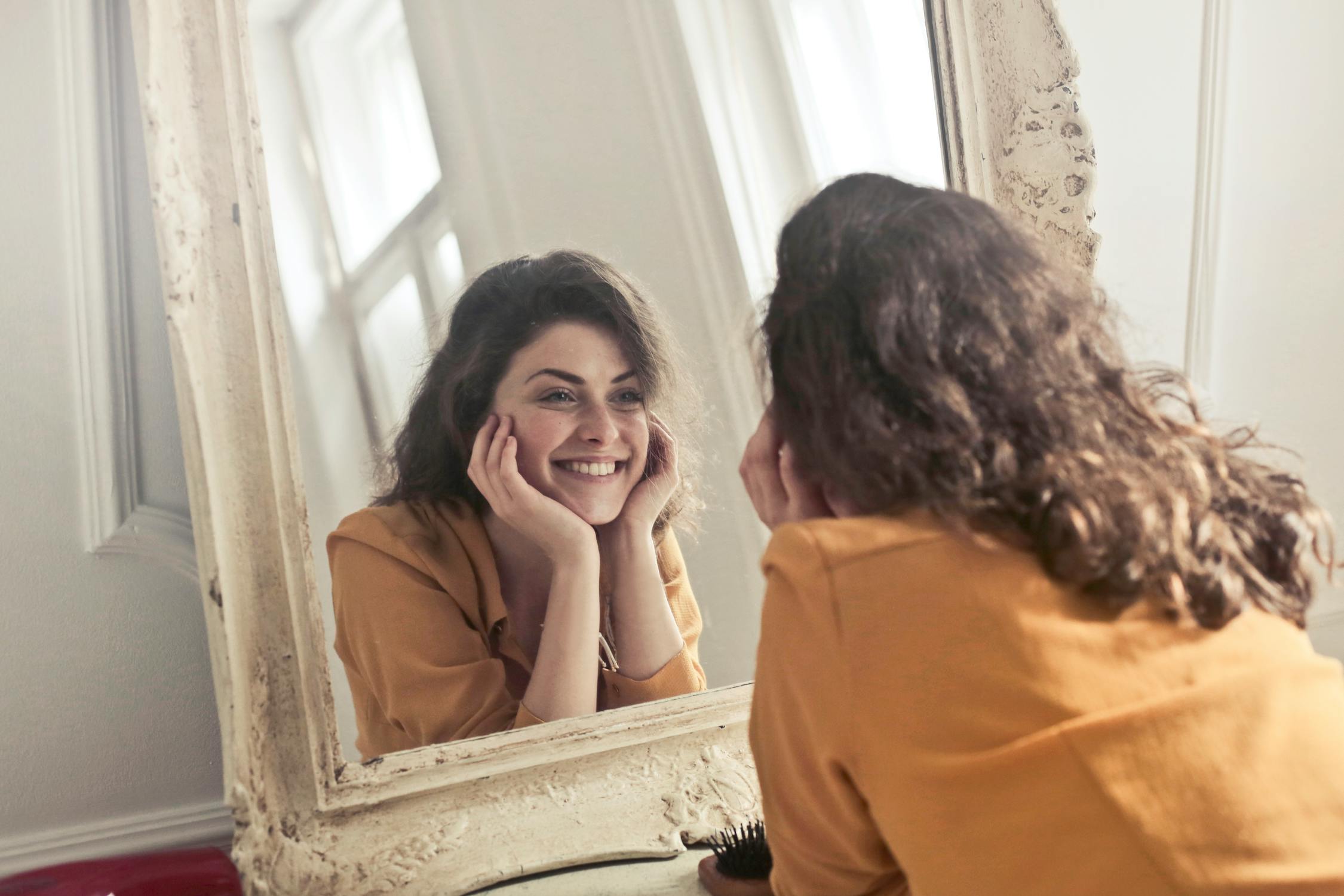 a woman smiling while looking in mirror