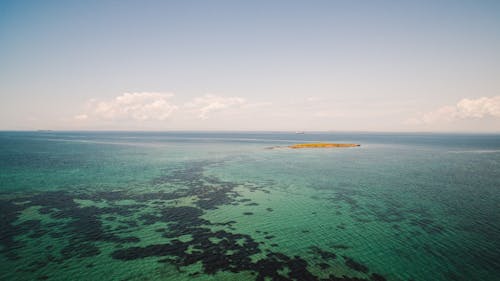 An Island Surrounded by Turquoise Water Under a Blue Sky