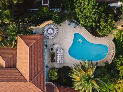 Free A stunning birds-eye view of a tropical resort featuring a swimming pool and lush greenery. Stock Photo