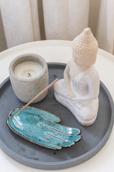 Serene home decor with a Buddha statue, candle, and incense tray for relaxation.