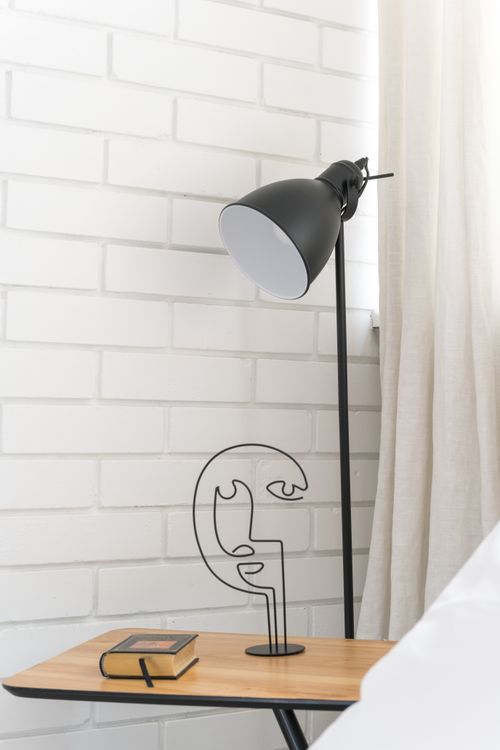 Free Elegantly styled room with a black floor lamp, abstract sculpture, and a small book on a side table. Stock Photo